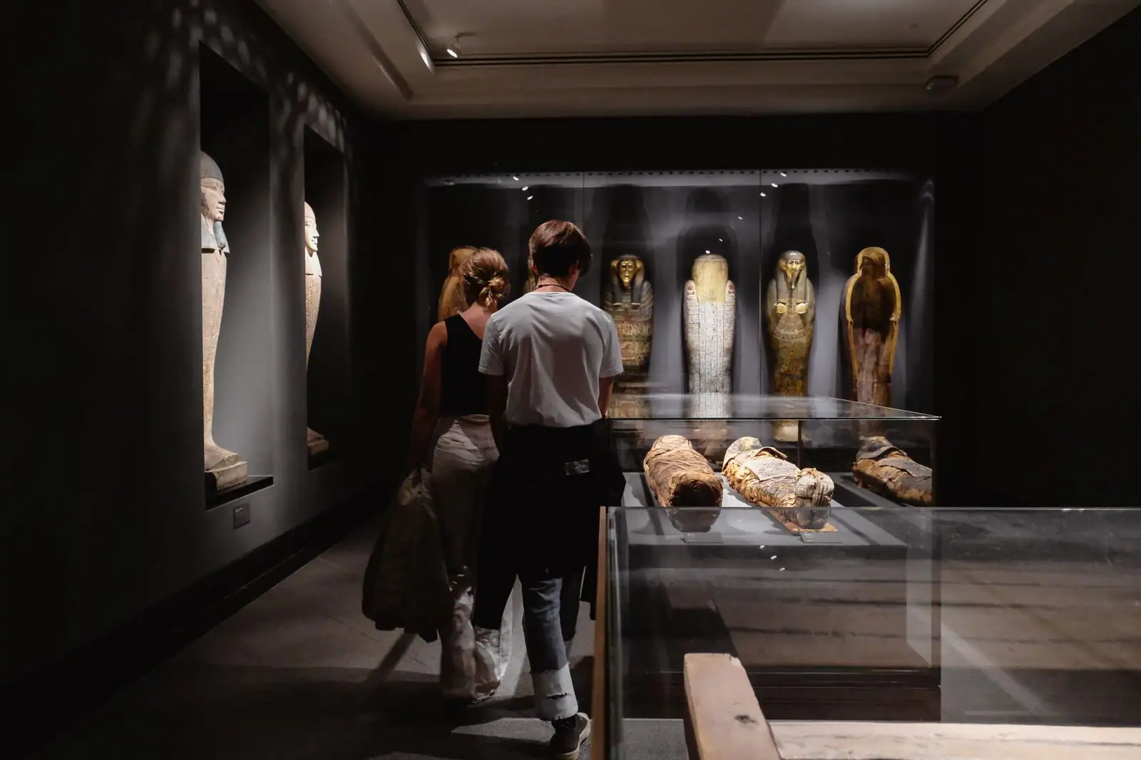 Visiteurs déambulant dans la salle d'exposition du musée du quai Branly à Paris en lumière tamisée