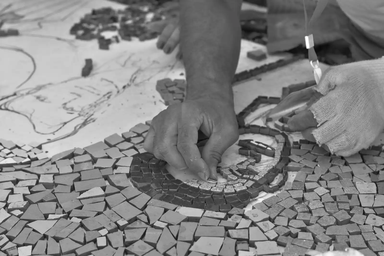 Mains assemblant des tesselles colorées sur un projet de mosaïque