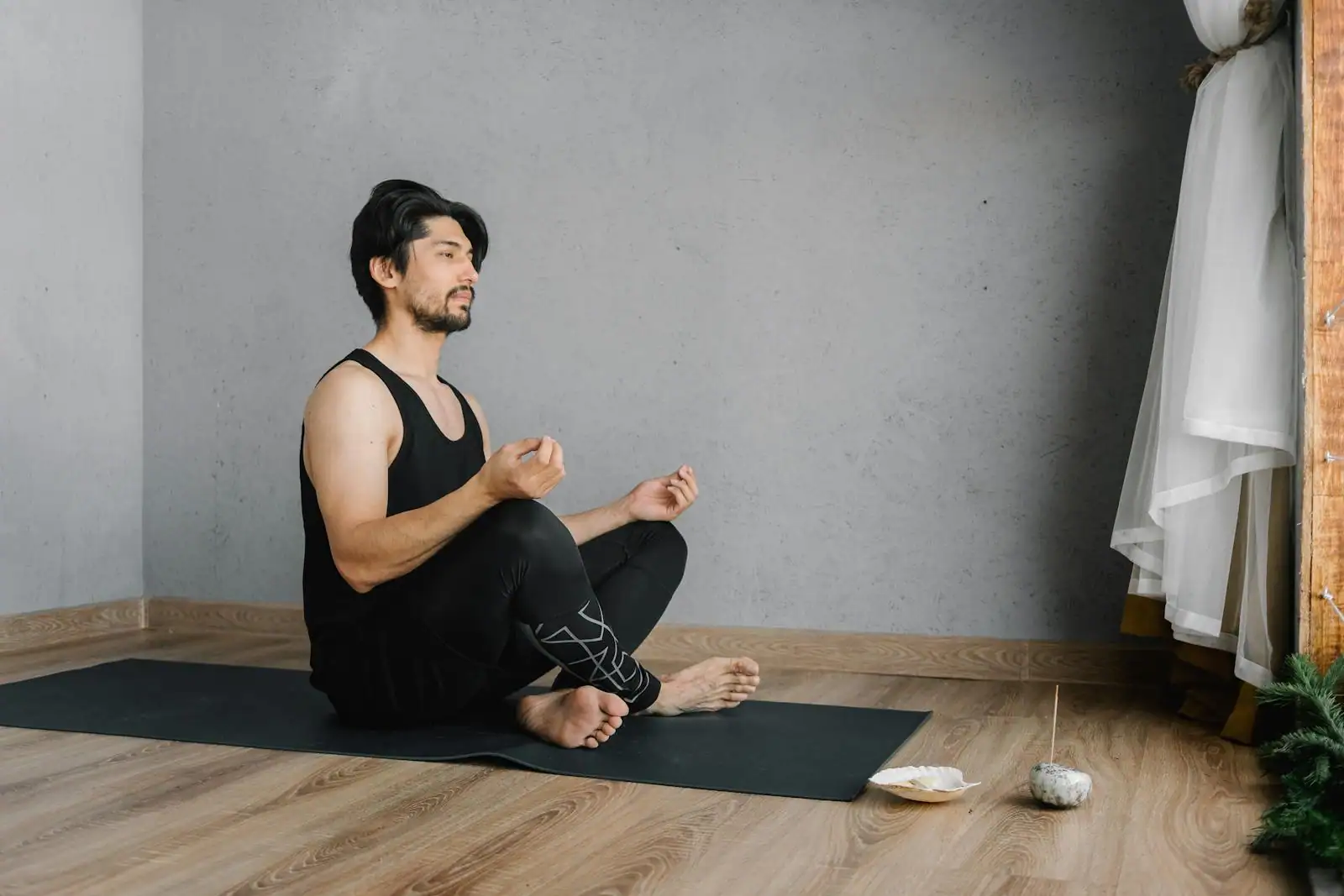 Personne assise en méditation, les yeux fermés, dans une pièce calme baignée d'une lumière douce.