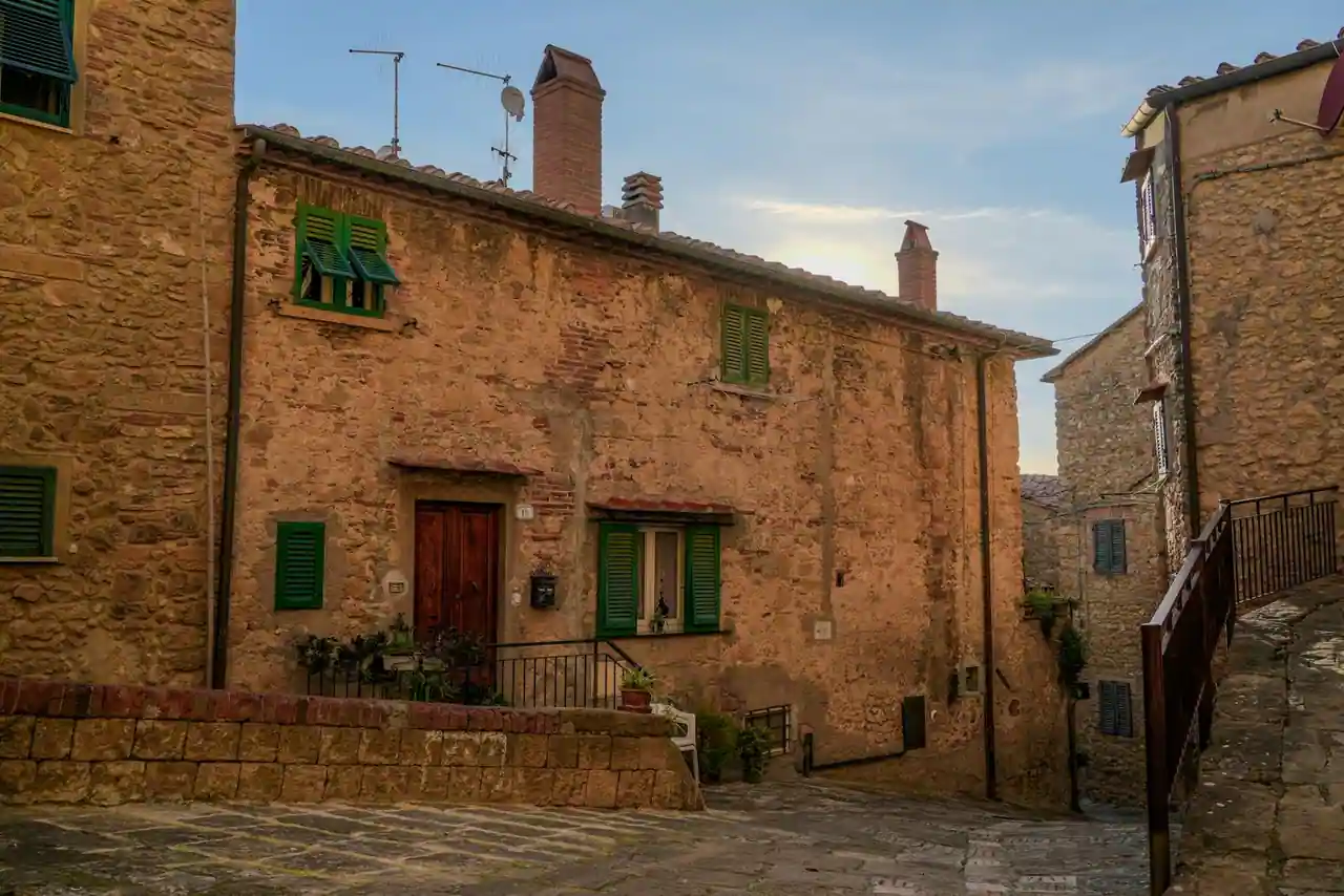 Reconstitution d'un village médiéval en pierre et bois, ruelle pavée, atelier d'artisan, lumière du matin