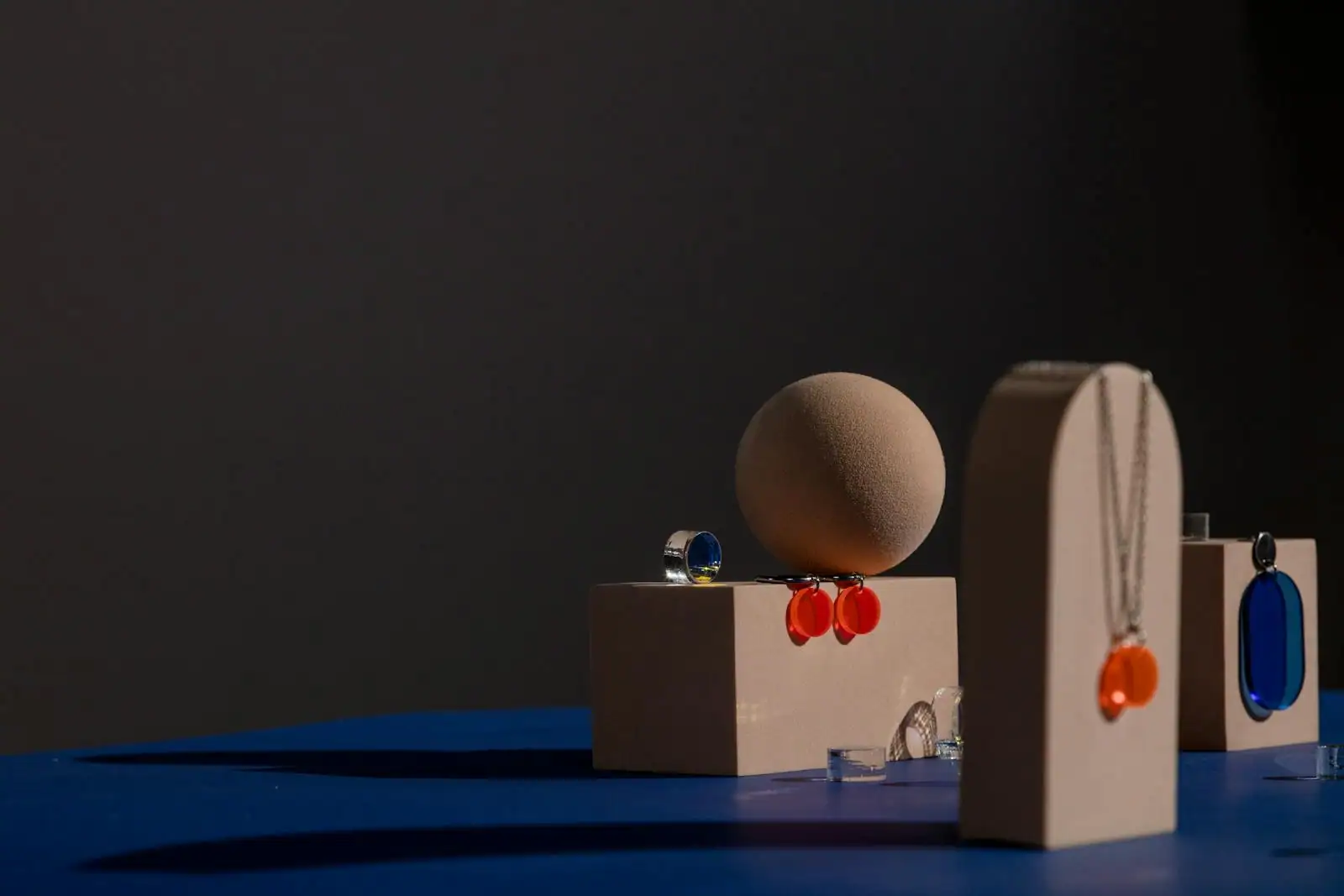 Sélection de bijoux fantaisie femme posés sur un présentoir clair, colliers dorés, créoles et bagues colorées en gros plan