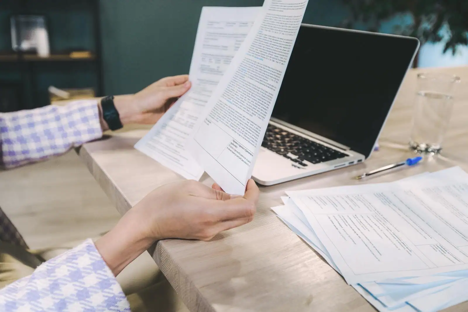 Personne attablée relisant son CV imprimé près d'un ordinateur portable
