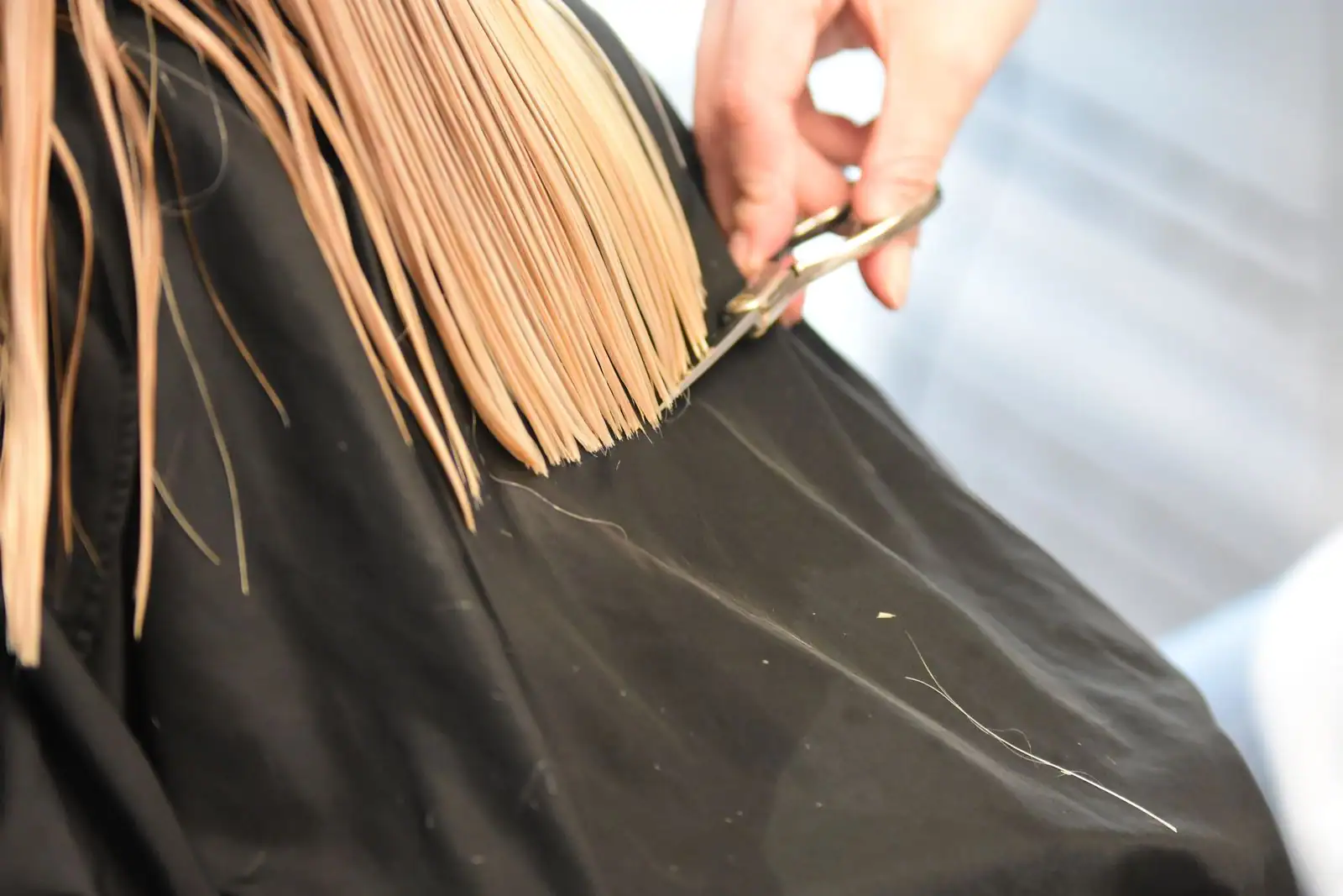 Coupe aux ciseaux d'une mèche de cheveux blonds dans un salon de coiffure
