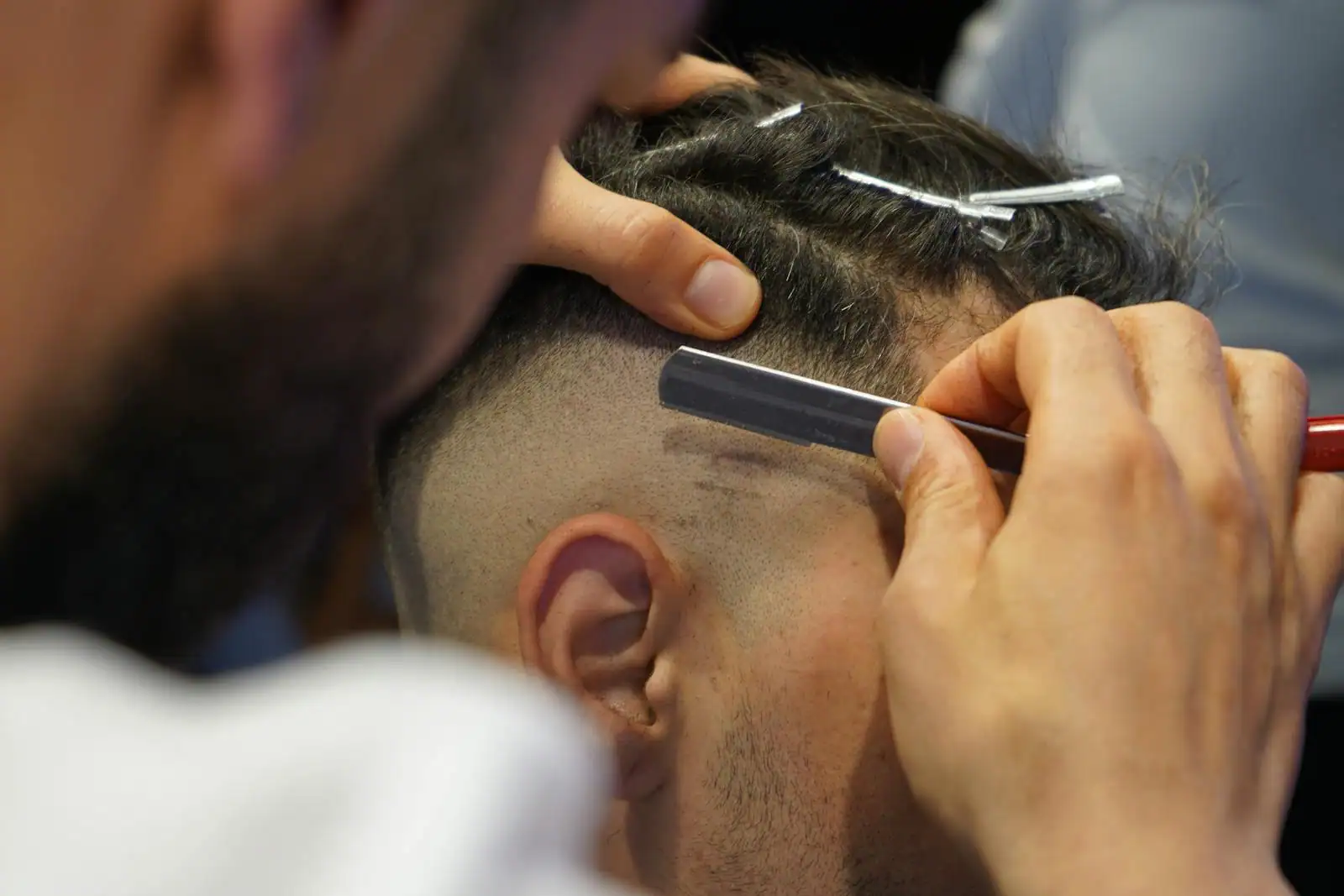 Homme se faisant réaliser un dégradé moderne chez le coiffeur, transition nette sur les côtés.