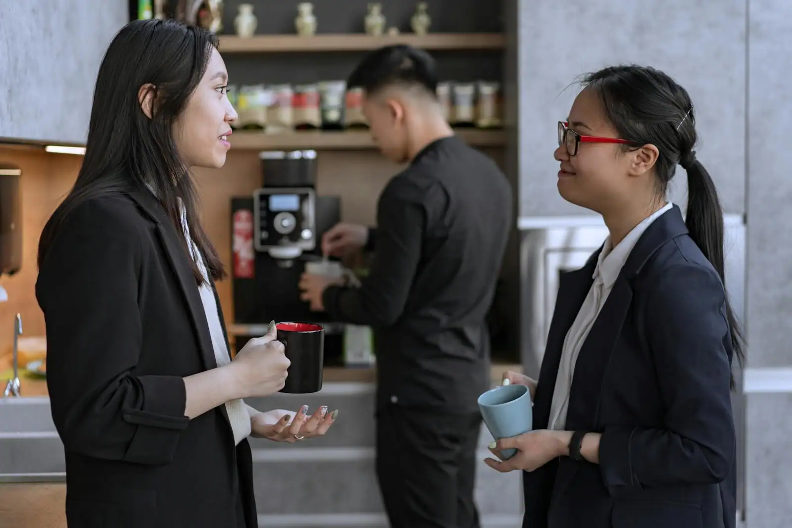 Deux collègues échangent un regard complice au bureau, autour d'un café