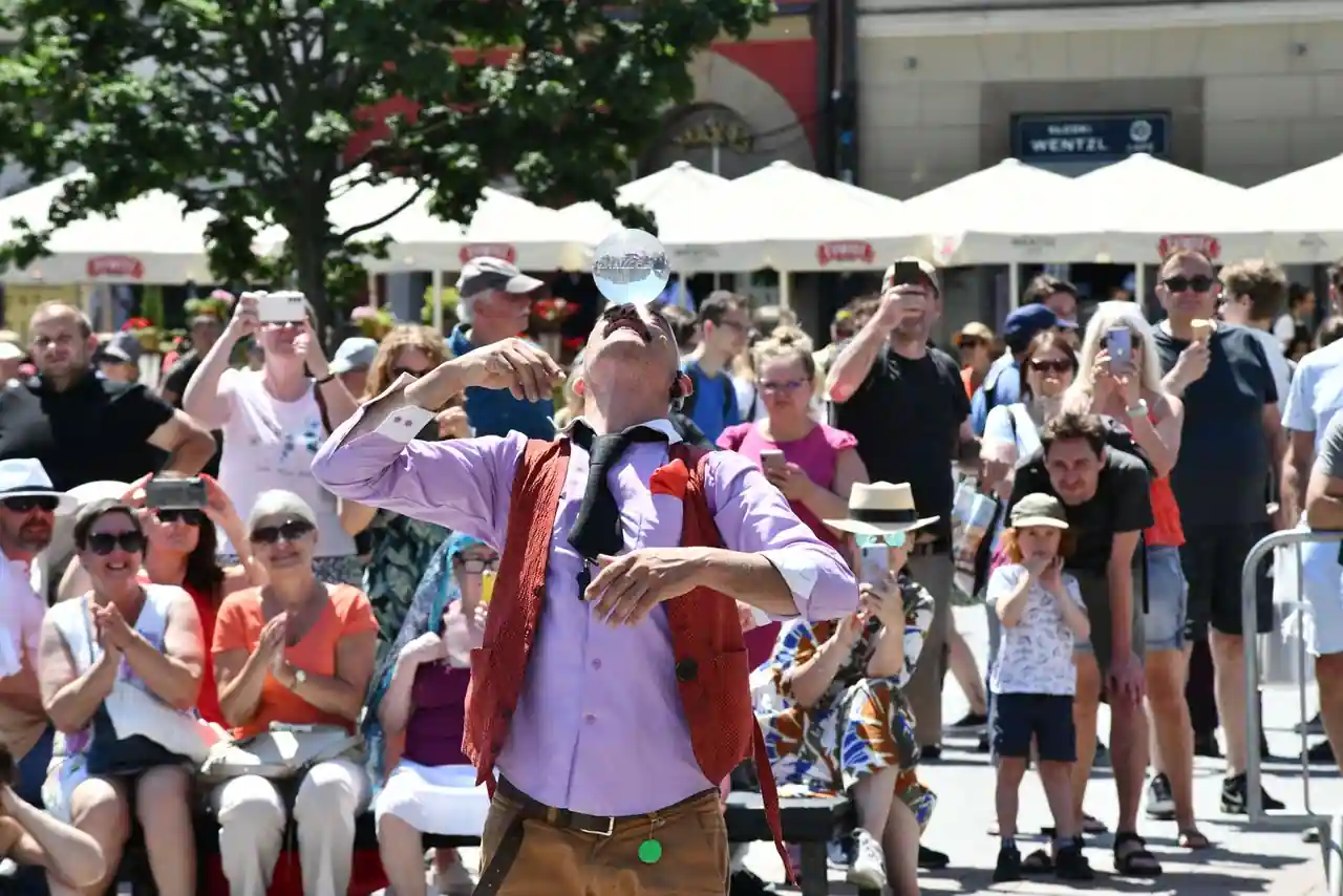 Artiste de rue en représentation devant une foule de spectateurs sur une place de ville ensoleillée