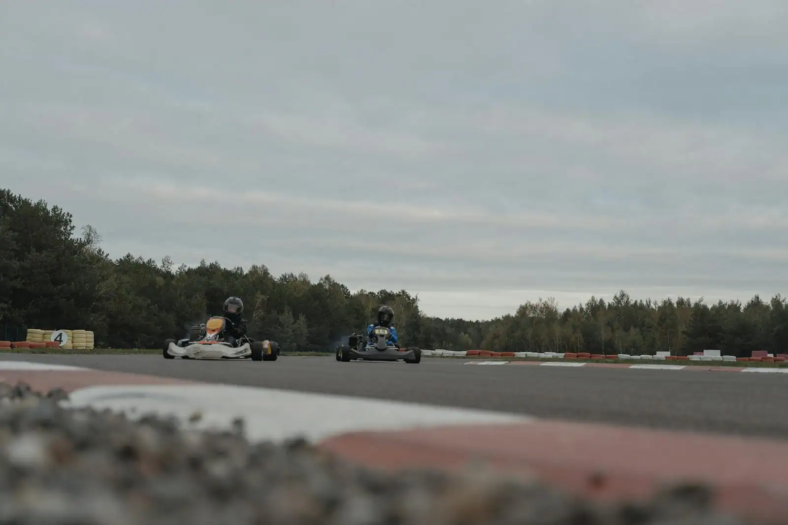 Pilote en combinaison et casque au volant d'un kart de loisir sur un circuit de plein air en plein virage.