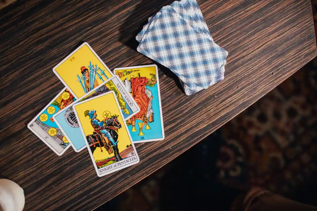 Cartes de tirage divinatoire illustrées posées sur une table en bois sombre, dans une ambiance feutrée