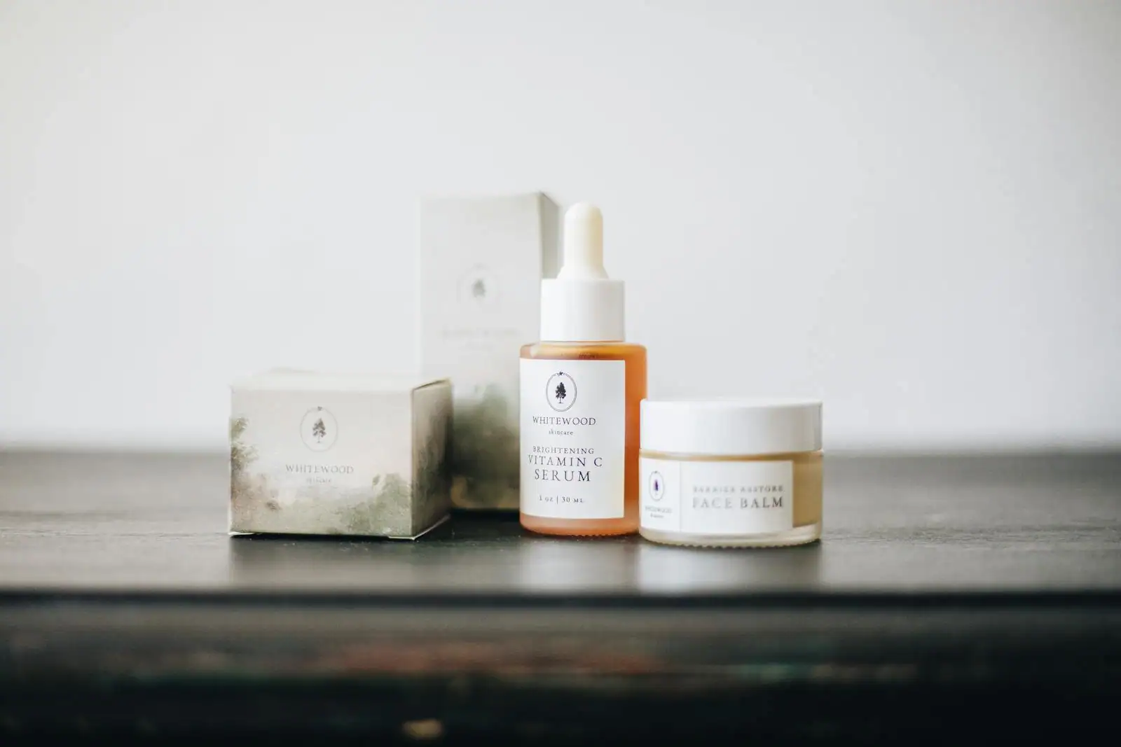 Produits de soin naturels — sérum et baume — aux flacons sobres, sur un plan en bois