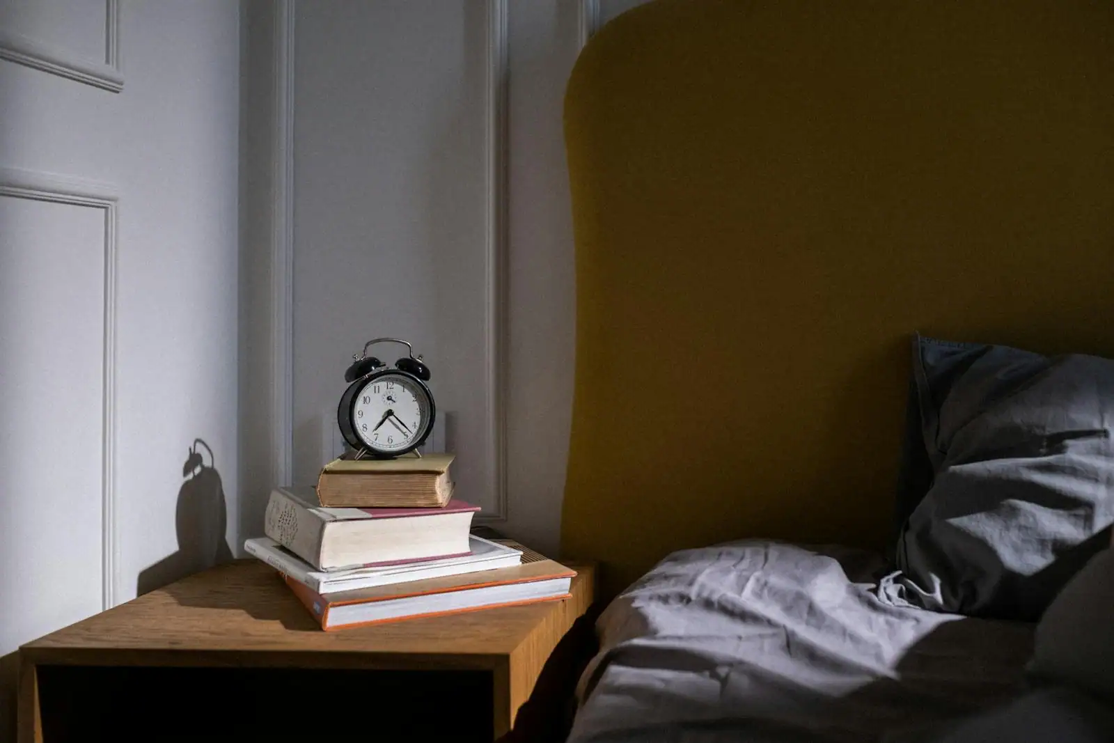 Table de chevet avec lampe douce, livre et tasse, ambiance feutrée avant le coucher