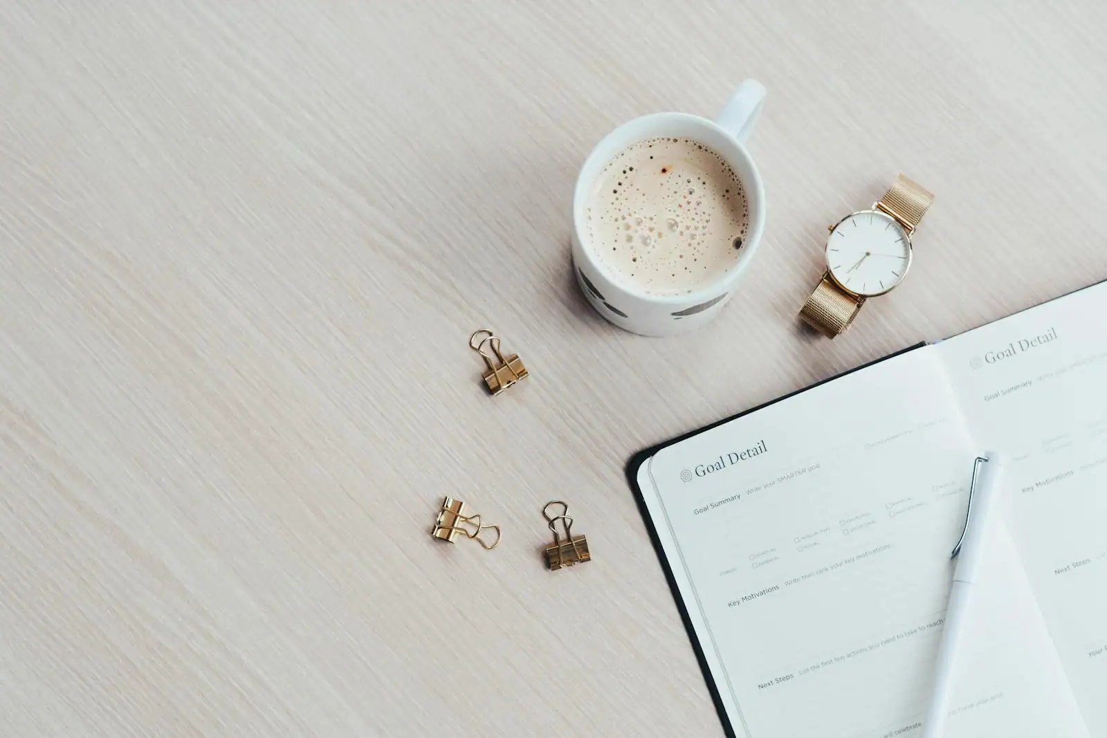 Carnet ouvert avec un planning de journée et une tasse de café sur un bureau clair
