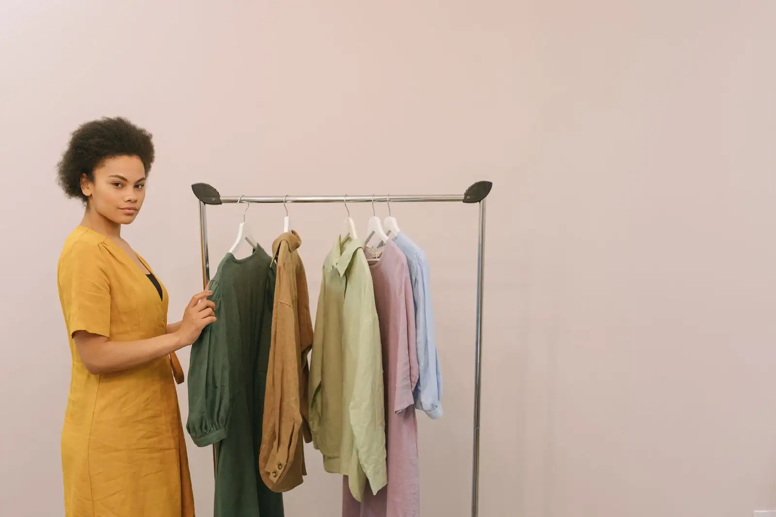 Jeune femme regardant des vêtements colorés sur un portant, dans une ambiance de shopping mode