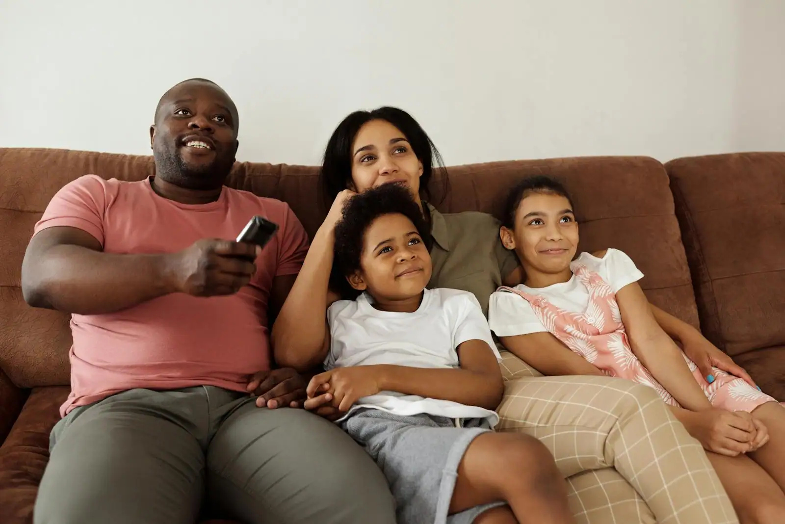 Famille réunie sur un canapé devant la télévision dans un salon chaleureux