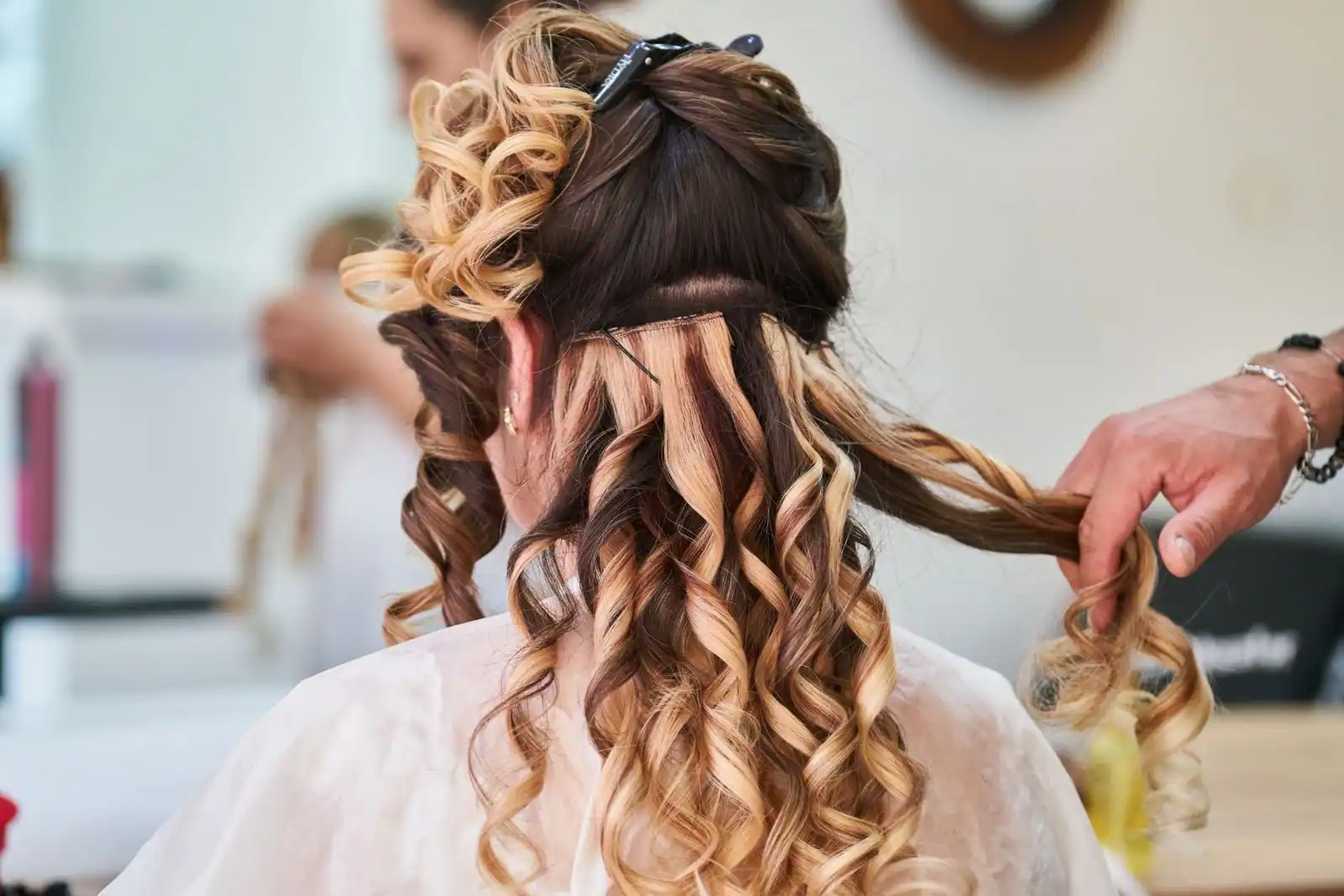 Cheveux longs bruns et bouclés parsemés de reflets caramel dorés, coiffés en salon