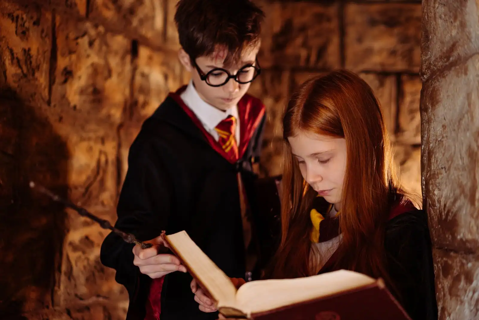 Enfant costumé en jeune sorcier avec une cicatrice en éclair dessinée sur le front et des lunettes rondes