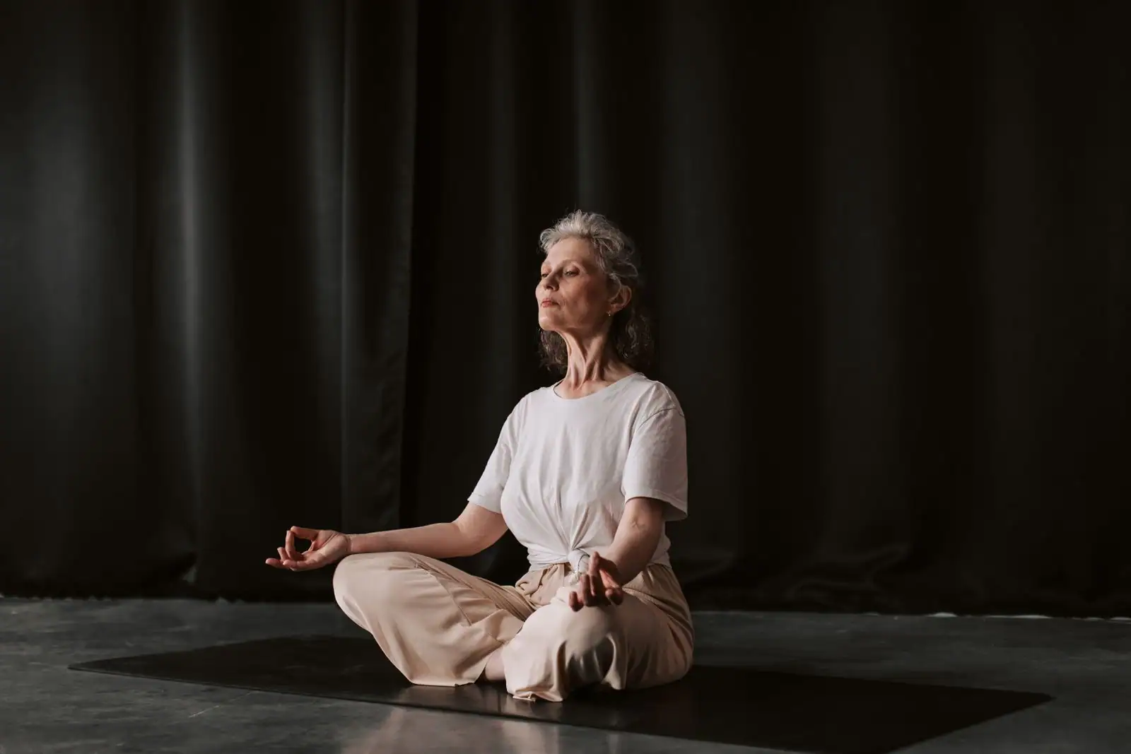 Femme assise en méditation, les yeux fermés, dans une lumière douce