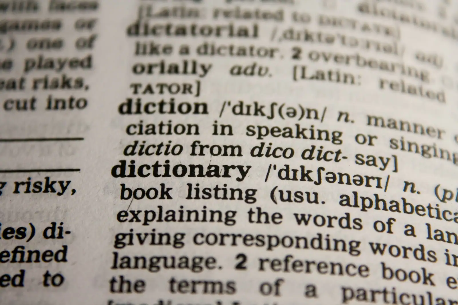 Gros plan sur la page d'un dictionnaire anglais, à l'entrée « dictionary » et sa transcription phonétique.
