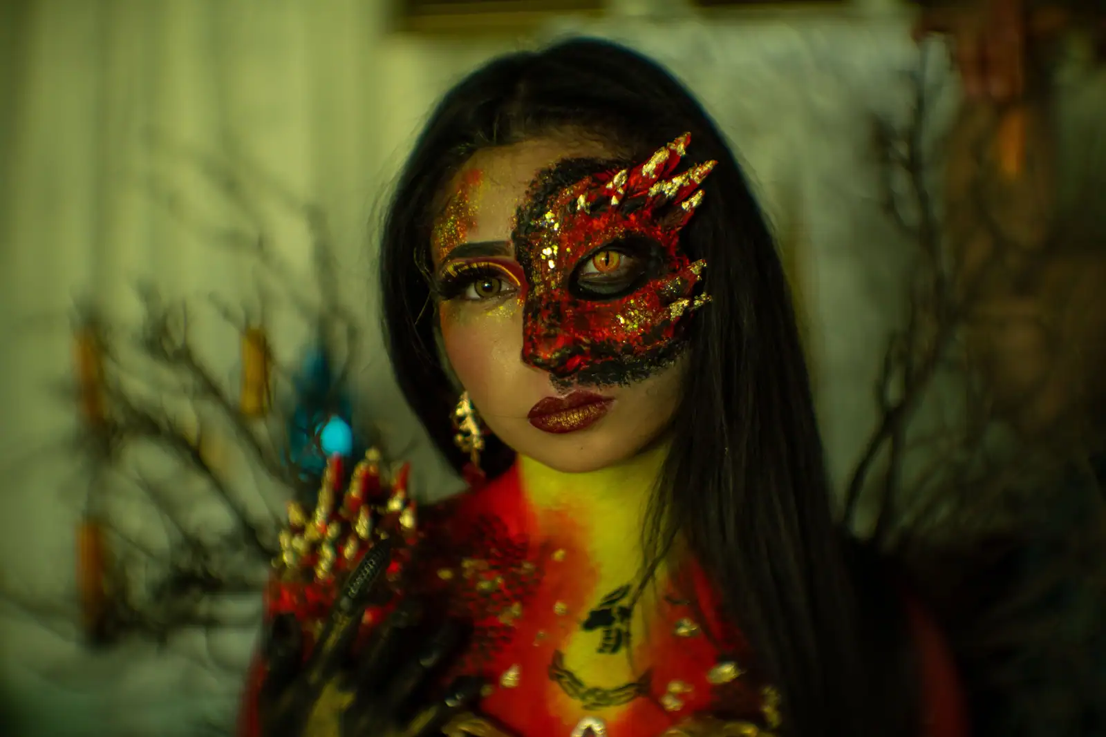 Maquillage de dragon sur la moitié du visage : écailles rouges et dorées, pointes de crête et œil reptilien